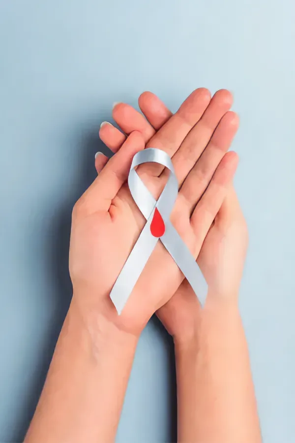 Close up of hands holding a white ribbon with a red drop illustration on it, signifying diabetes treatment from Vida Integrative Health of Miami in Miami.