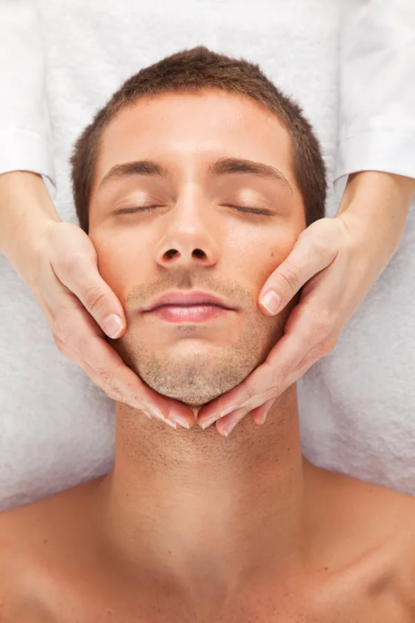 Close-up of a man with a clinician's hands on his face, receiving a HydraFacial treatment in Miami.