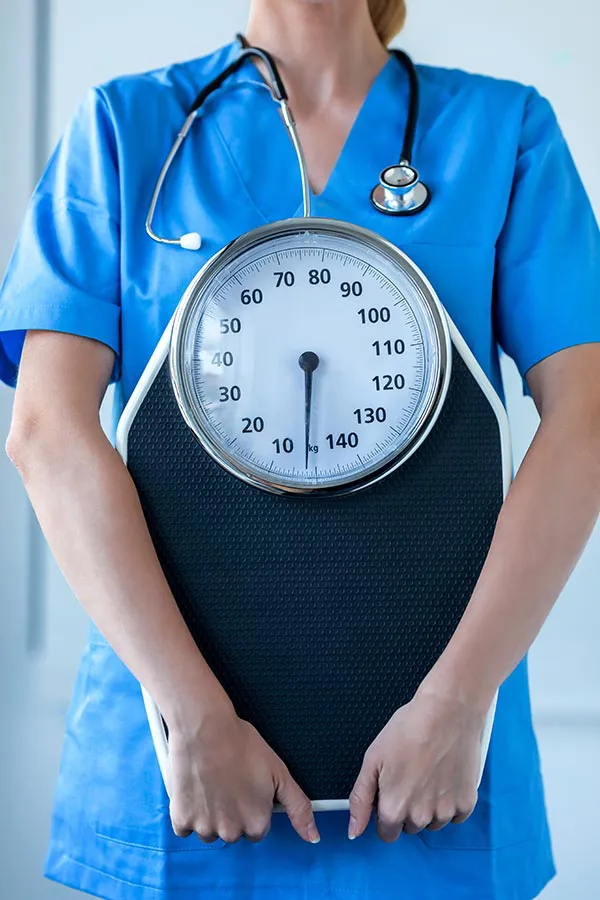 A nurse in scrubs holds a scale, signifying weight loss treatments from Vida Integrative Health of Miami in Miami.