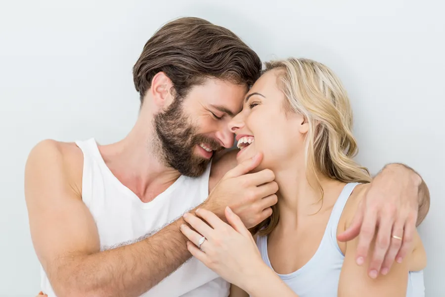 A close up of a man and woman looking in white underwear lying in bed and smiling at each other, signifying success from erectile dysfunction treatment from Vida Integrative Health of Miami in Miami.