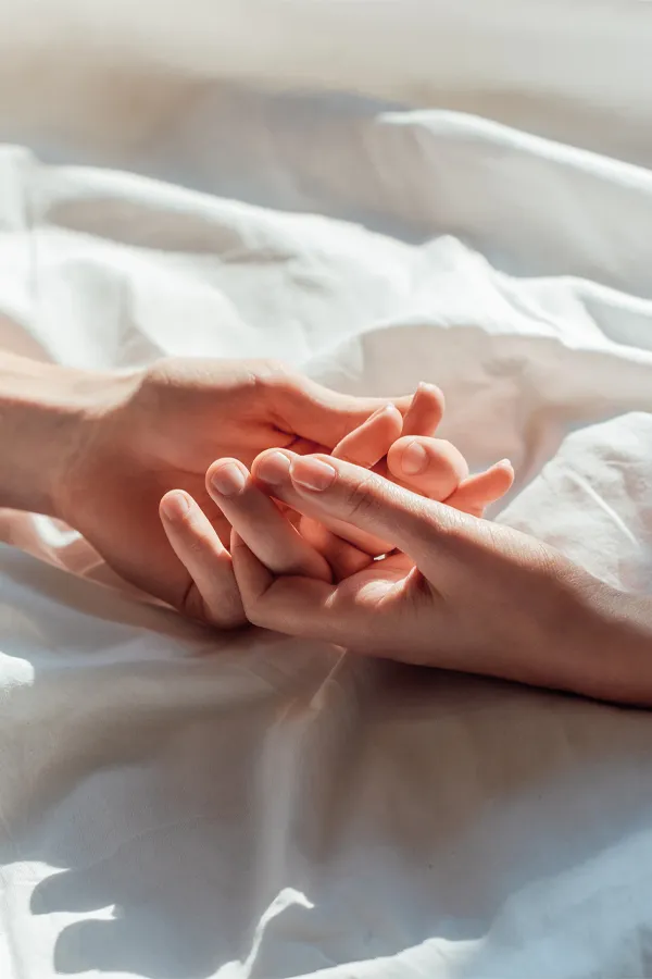 A close up of a man and a woman's interlocking fingers on top of a sheet, signifying treatment for sexual wellness from Vida Integrative Health of Miami in Miami.