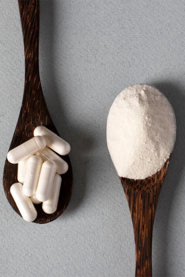 Two wooden spoons on a table, on with white powder and one with capsules, representing peptide therapy from Vida Integrative Health of Miami in Miami.