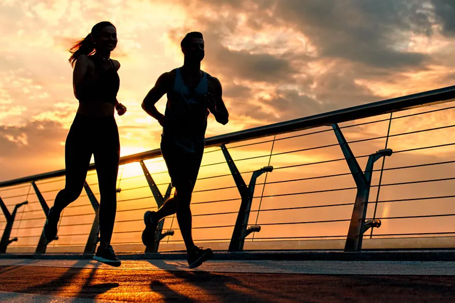 A couple jogging on a bridge at sunrise, representing performance enhancing peptide therapy from Vida Integrative Health of Miami in Miami.