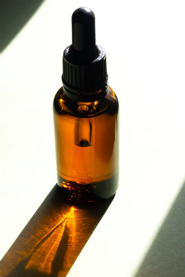 A brown dropper bottle on a table lit by sunlight, representing performance enhancing peptide treatment from Vida Integrative Health of Miami in Miami.