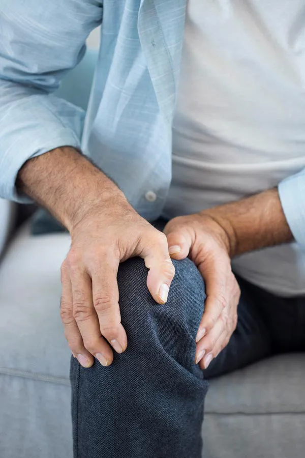 A close-up of a man holding his knee while experiencing pain from osteoporosis. Get osteoporosis treatment from Vida Integrative Health of Miami in Miami.